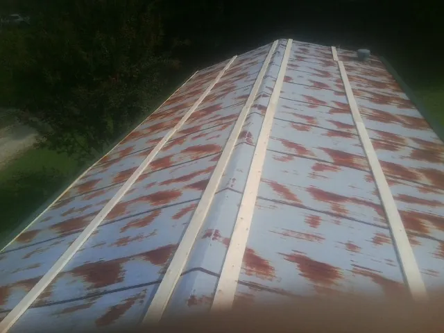 Rusted metal roof panels with new wood purlins before replacement — Storm Damage Roof Repair in Collins by Roofing Brothers