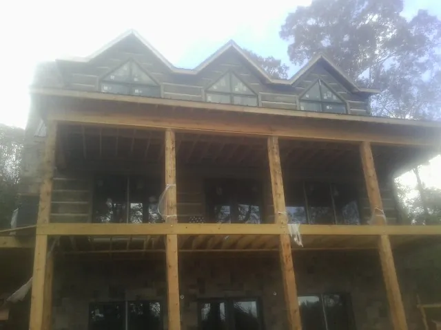 Dormers and porch framing on a large log home under construction — Roof Coating work by our crew in Collins